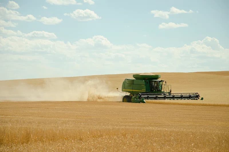 US farm field with harvester collecting crops during harvest season